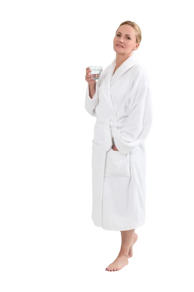 Kvinna i badrock med ett glas vatten — Stockfoto