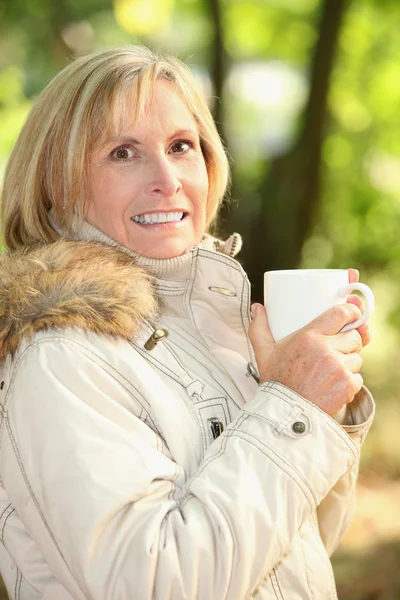 Зрелая женщина пьет кофе на открытом воздухе — стоковое фото