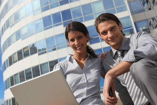 Professionell par använder en bärbar dator utanför en kontorsbyggnad — Stockfoto