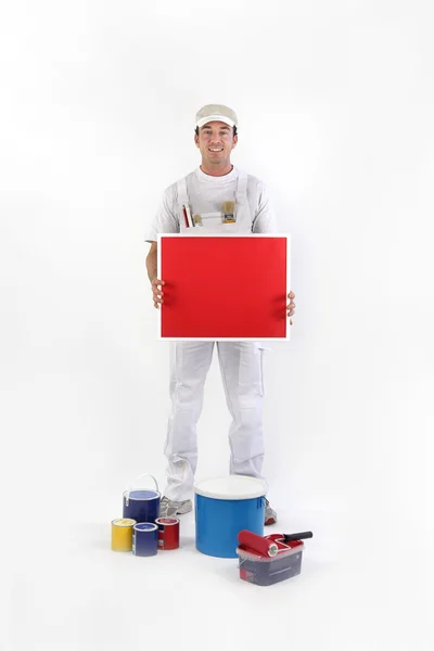 Pintor segurando um cartaz vermelho — Fotografia de Stock