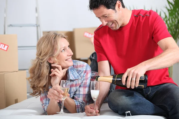 Par firar flytta in i nya hem med champagne — Stockfoto