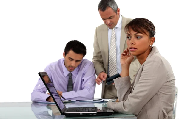 Junge Geschäftsfrau mit Laptop und männlichen Kollegen im Hintergrund — Stockfoto
