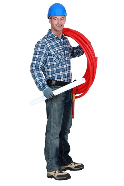 Portrét hezký instalatér nesoucí červené hadice izolovaných na bílém — Stock fotografie