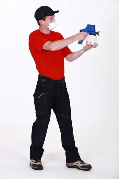 Человек в маске для лица при использовании распылителя краски — стоковое фото
