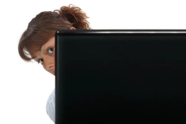 Vrouw "peering" rond haar laptop — Stockfoto