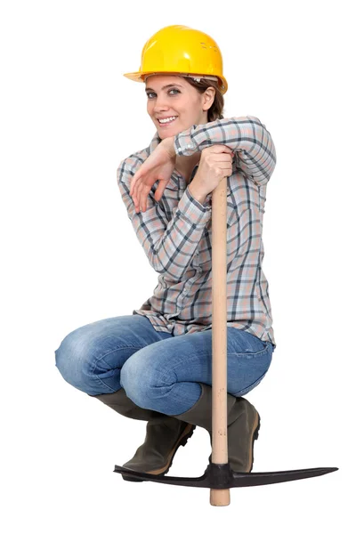 Woman kneeling by a pickax — Stock Photo, Image
