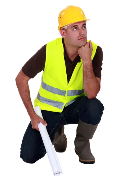 Trabalhador pensivo agachado no fundo branco — Fotografia de Stock