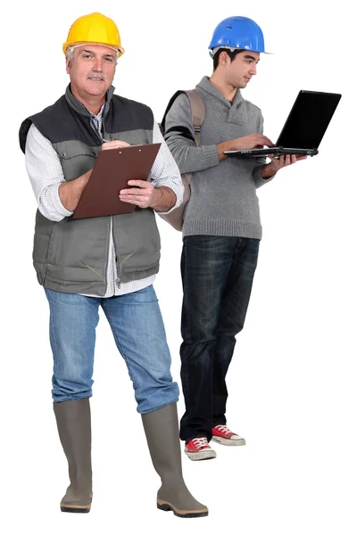 Senior hantverkare anteckningar medan unga hantverkare arbetar på sin laptop — Stockfoto