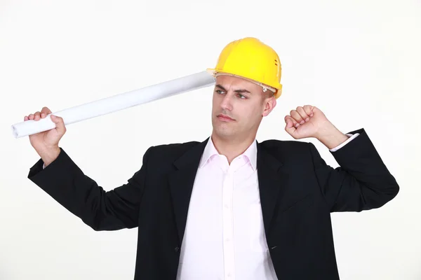 Architect holding blueprints stretching himself against studio background — Stock Photo, Image