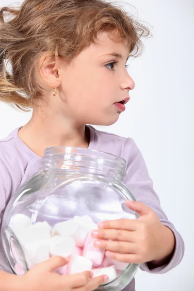 Little girl holding a jar full of marshmallows. — Stock Photo, Image