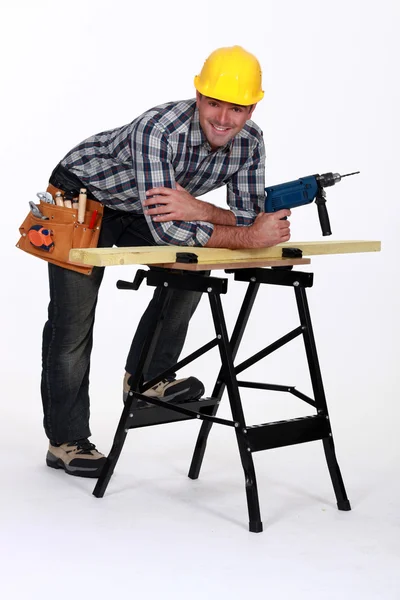 Плотник с дрелью небрежно опираясь на рабочую скамейку — стоковое фото