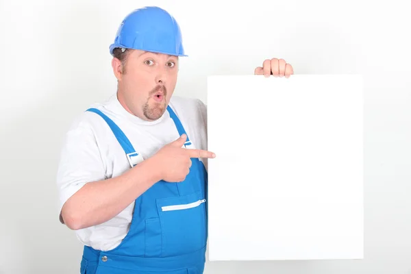 Surprised tradesman holding a blank sign — Stock Photo, Image