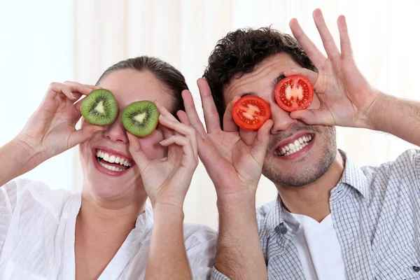 Забавная пара, закрывающая глаза фруктами — стоковое фото