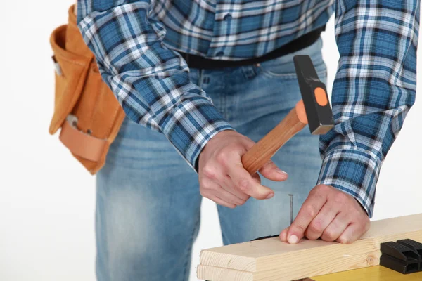 Man hammering nail into wood — Stock Photo, Image