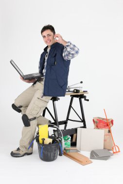 Tiler with a laptop and mobile phone clipart