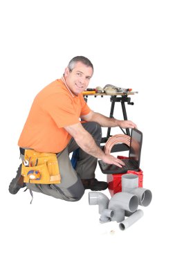 Plumber with a laptop and various tools of the trade clipart