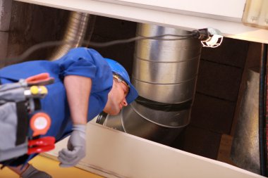 Plumber standing under a heating duct clipart