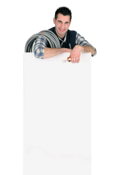 Electrician stood by publicity panel — Stock Photo, Image