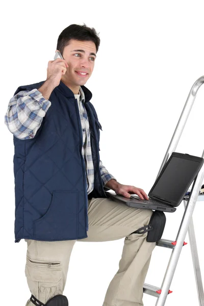 Dekorator co telefon podczas korzystania z laptopa — Zdjęcie stockowe