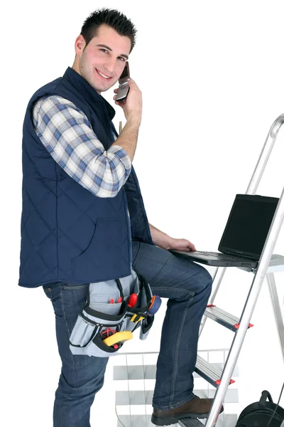 Un comerciante posando con sus herramientas, materiales de construcción y su portátil —  Fotos de Stock