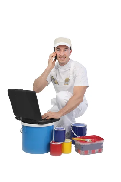 Decorator with laptop and tins of paint — Stock Photo, Image