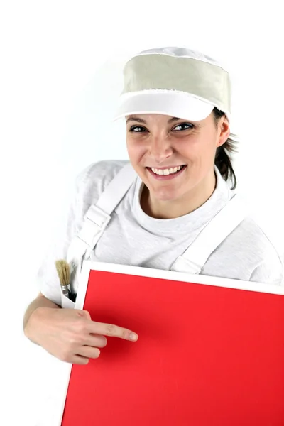 Glad kvinna dekoratör pekar på röda panel — Stockfoto