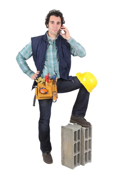 Портрет торговца, говорящего по мобильному телефону, и его нога, стоящая на блоке — стоковое фото