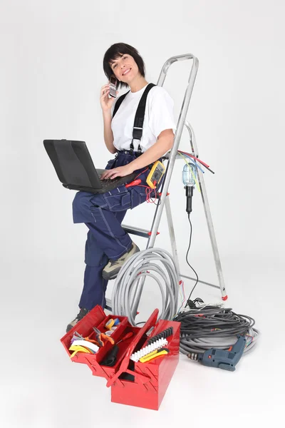 Junior craftswoman with laptop and miscellaneous tools — Stock Photo, Image