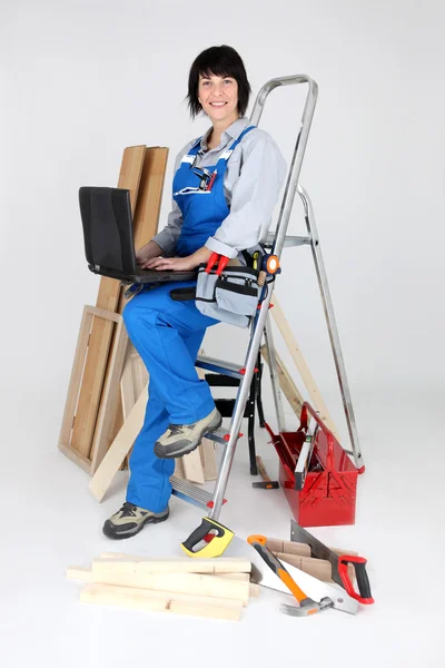 Vrouwelijke timmerman met ladder en laptop — Stockfoto