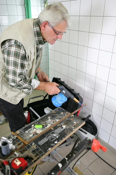 Gråhåriga handyman med blåslampa — Stockfoto