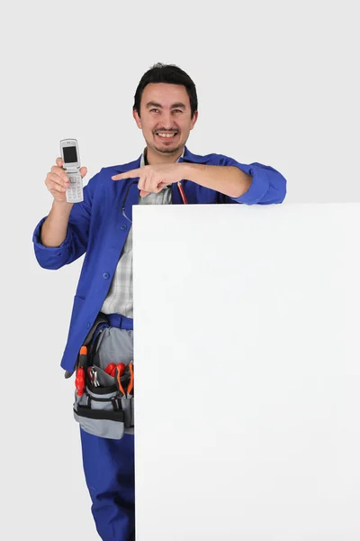 Uomo con lavagna bianca, cintura degli attrezzi e cellulare — Foto Stock