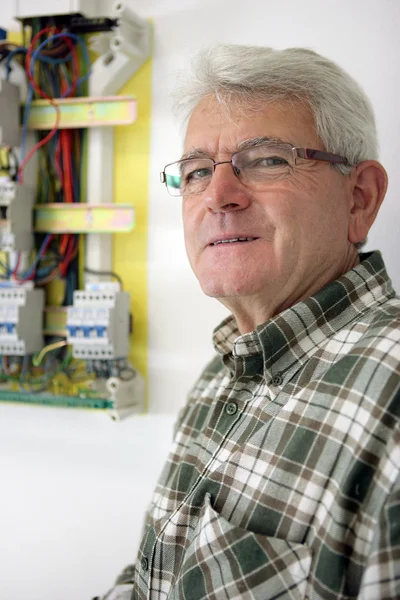 Senior elektricien permanent door fusebox — Stockfoto