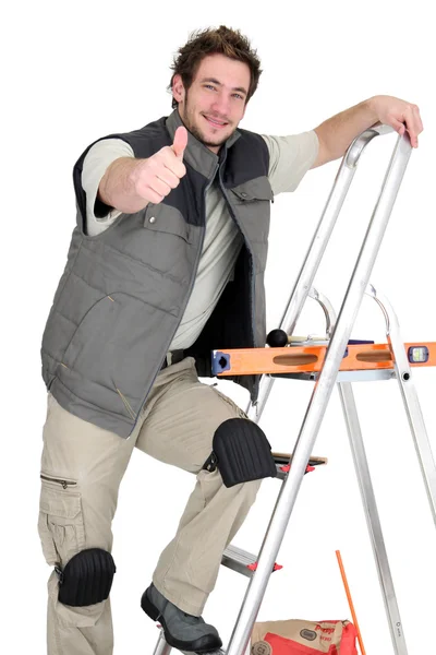 Obkladač lezení žebřík, zatímco dává palec nahoru — Stock fotografie