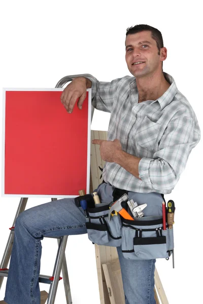 Carpinteiro posando com cartaz vermelho — Fotografia de Stock