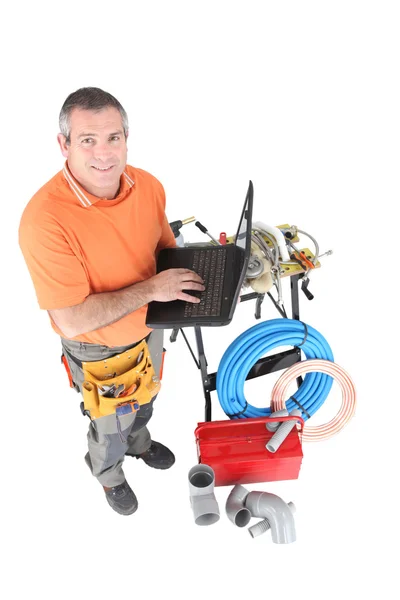 Workman posing with his laptop, tools and building materials — Stock Photo, Image