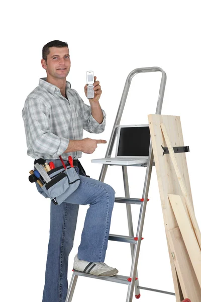 Плотник стоит у лестницы с мобильным телефоном — стоковое фото