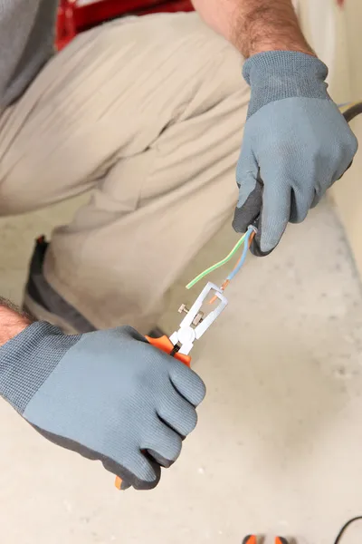 Электрик раздевает провода плоскогубцами — стоковое фото