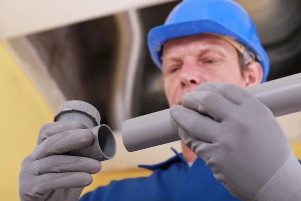 Encanador segurando duas partes de tubo de plástico — Fotografia de Stock