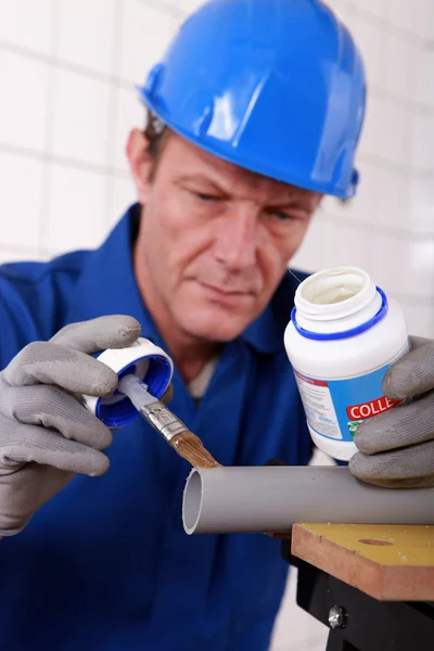 Encanador aplicando cola para tubo de plástico — Fotografia de Stock