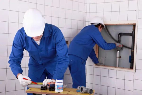 Deux plombiers travaillant dans une salle de bain publique — Photo