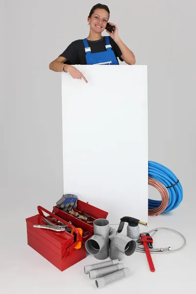 Female plumber with a board left blank for your message — Stock Photo, Image
