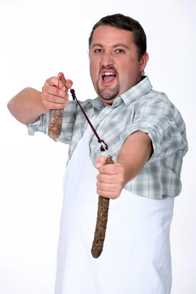 Angry butcher fighting with sausages — Stock Photo, Image