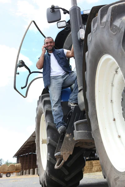 Γεωργός σε ελκυστήρα χρησιμοποιώντας ένα κινητό τηλέφωνο — Φωτογραφία Αρχείου