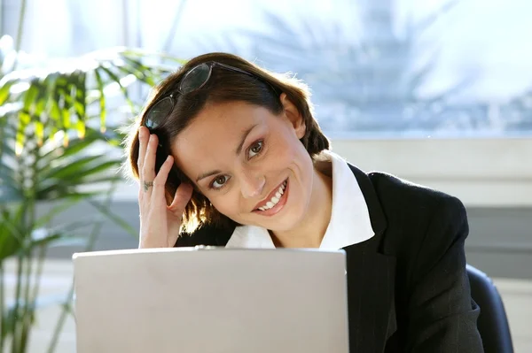 Glad brunett sitter vid hennes skrivbord — Stockfoto