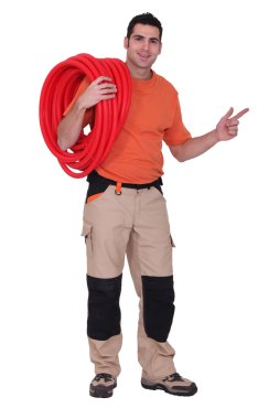 Plumber with coiled pipe pointing clipart