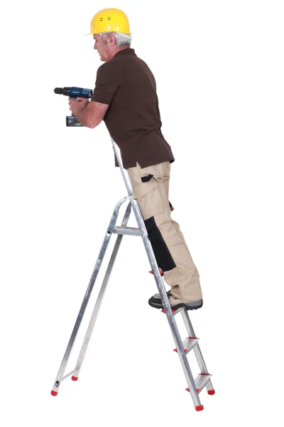Carpinteiro sênior levantou-se escada com broca — Fotografia de Stock