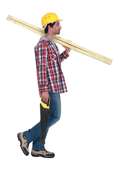 Řemeslník držící dvě dřevěná prkna a pilu — Stock fotografie