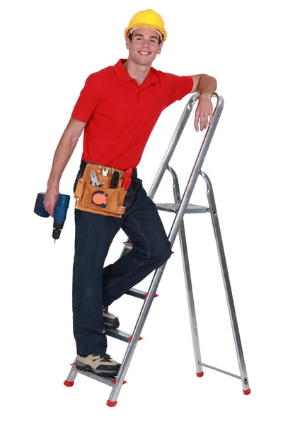 Junger Handwerker steht auf einer Leiter und hält eine Schraubenpistole in der Hand — Stockfoto