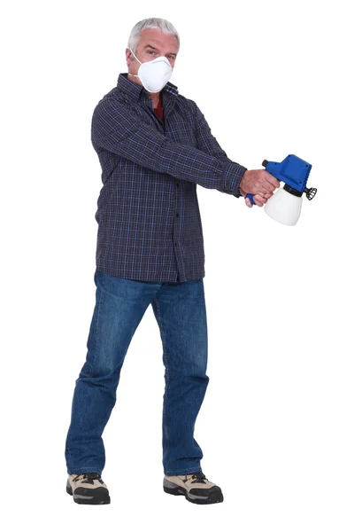 Tradesman segurando uma pistola de pulverização e usando uma máscara — Fotografia de Stock