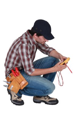 A kneeled electrician with a voltmeter. clipart